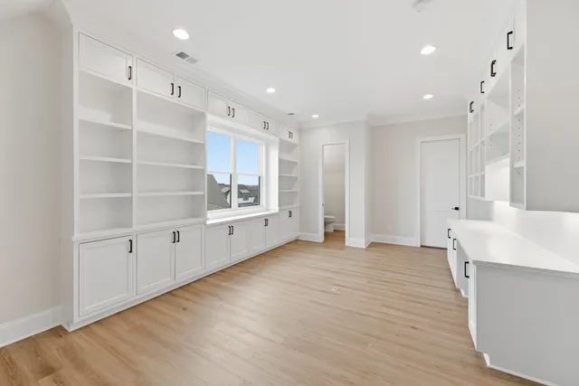 a view of an empty room with wooden floor and windows