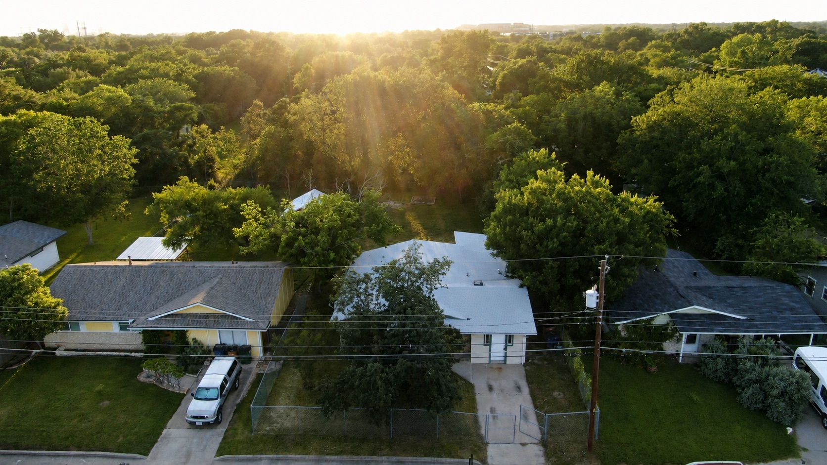1060 Gardner Road Austin, TX 78721 - Photo 1 of 19 An aerial perspective reveals a quiet neighborhood nestled among a canopy of mature trees under a radiant sky.
