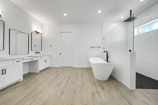 a large white kitchen with a white countertops a sink and stainless steel appliances