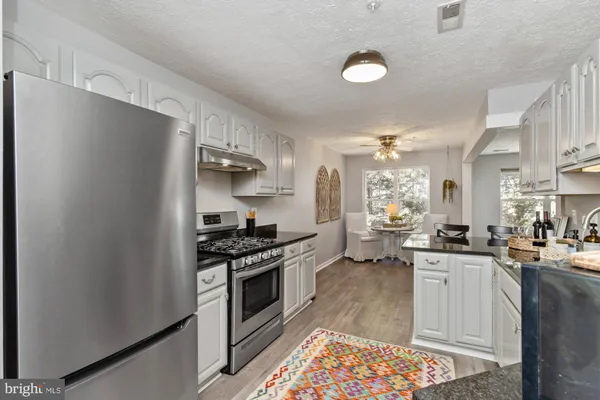 a kitchen with stainless steel appliances kitchen island granite countertop a sink stove and refrigerator