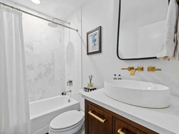 a bathroom with a granite countertop sink a toilet a mirror and shower