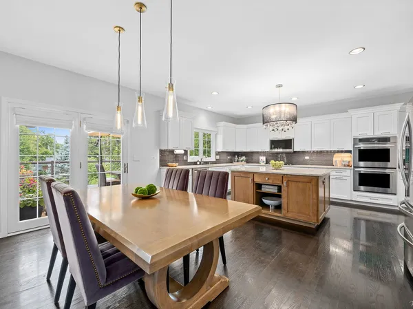 a kitchen with stainless steel appliances a dining table chairs and a wooden floor