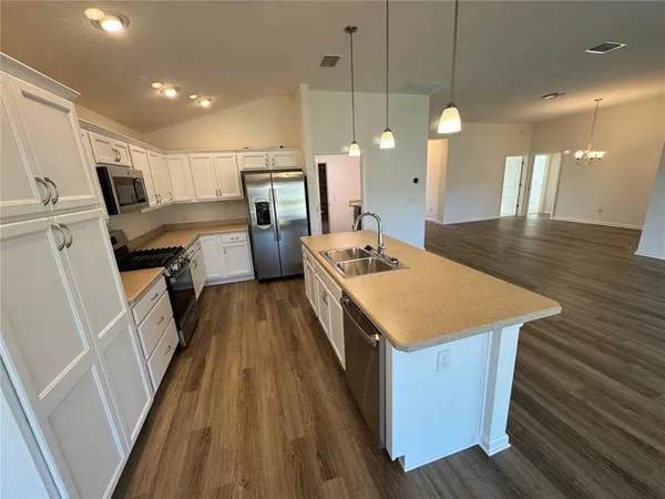 a kitchen with a sink a counter top space stainless steel appliances and a chandelier