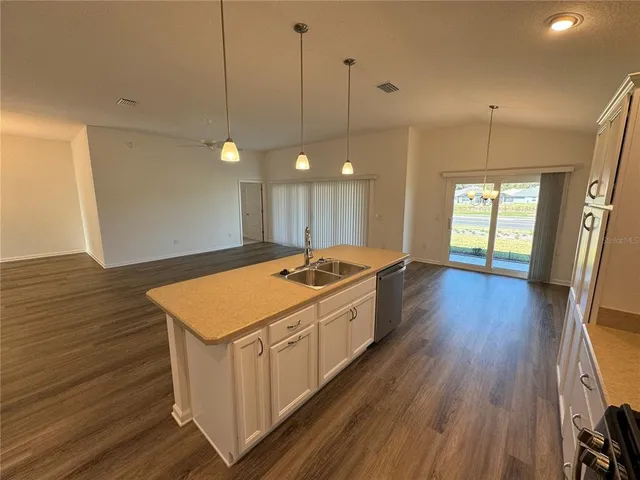 a large kitchen with a stove a sink dishwasher and a large refrigerator with wooden floor