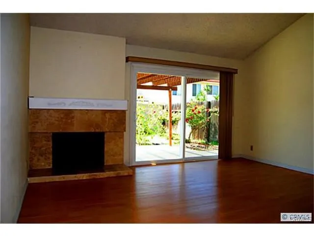 a view of empty room with wooden floor and fireplace