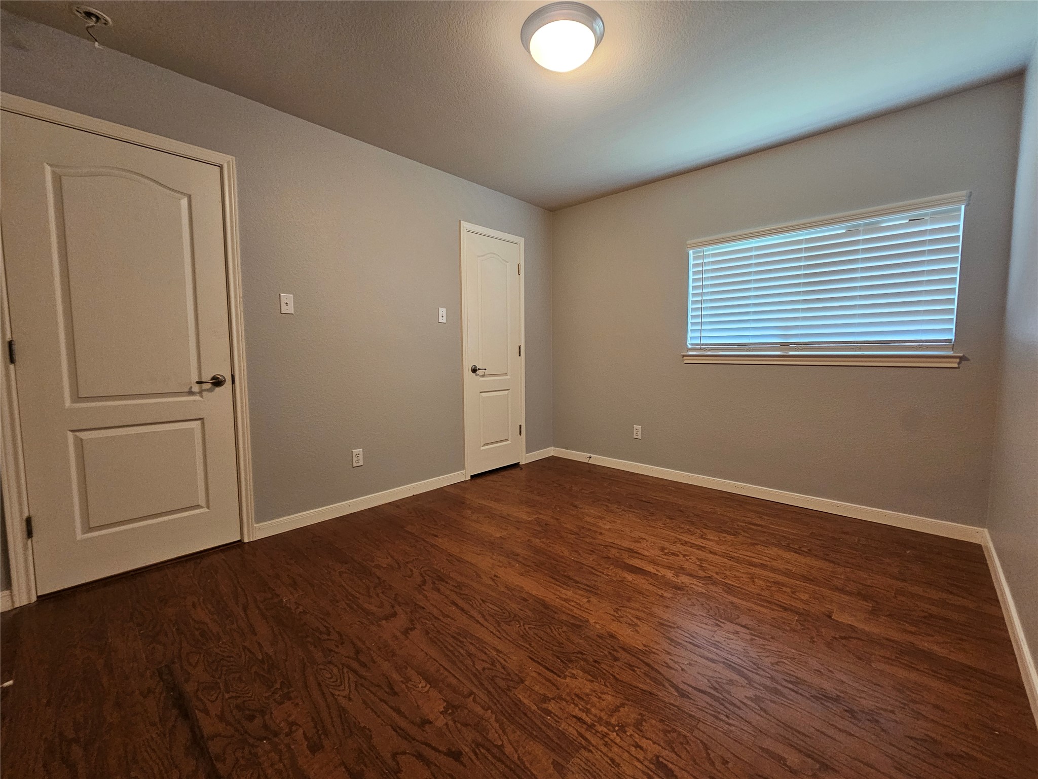 2035 Intrepid Drive Buda, TX 78610 - Photo 19 of 26 Rich hardwood floors complement neutral walls in this inviting bedroom.