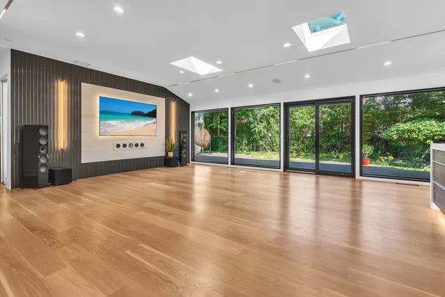 an empty room with large windows and a ceiling fan