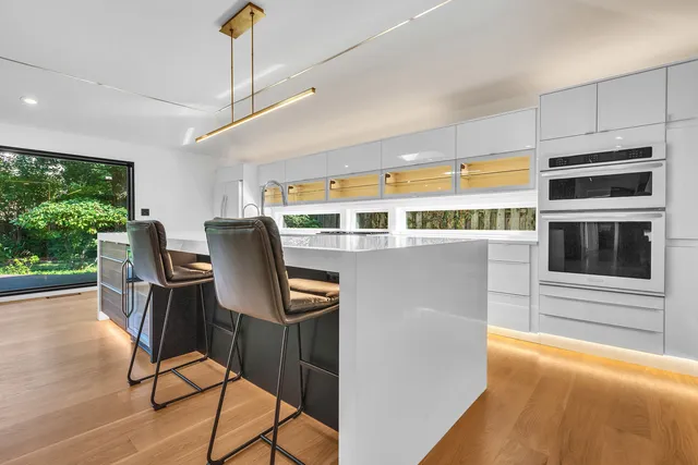 a kitchen with stainless steel appliances granite countertop a stove a refrigerator a microwave oven with a dining table and chairs with wooden floor
