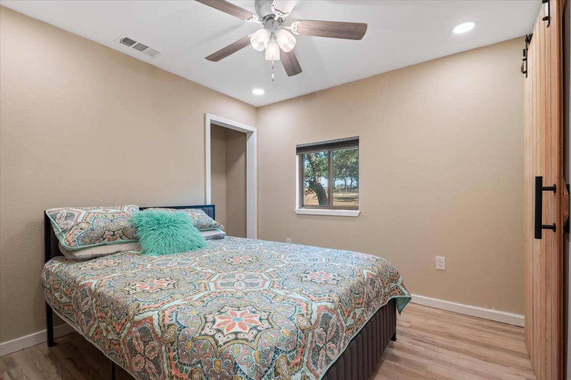 215 Go Away Road Blanco, TX 78606 - Photo 14 of 29 a bedroom with a large bed and a chandelier