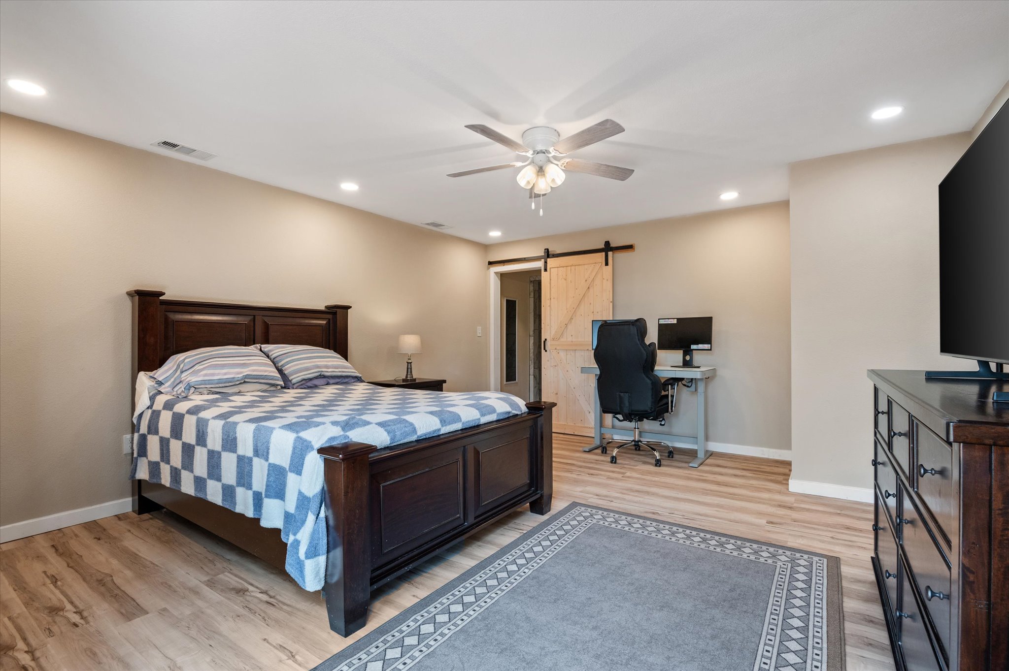 215 Go Away Road Blanco, TX 78606 - Photo 17 of 30 Primary Bedroom, dded in 2023, with ceiling fan and vinyl wood like flooring, walk-in closet and in-suite full bath. Even room for a desk! aRecessed lighting and french doors that lead to the backyard porch deck.