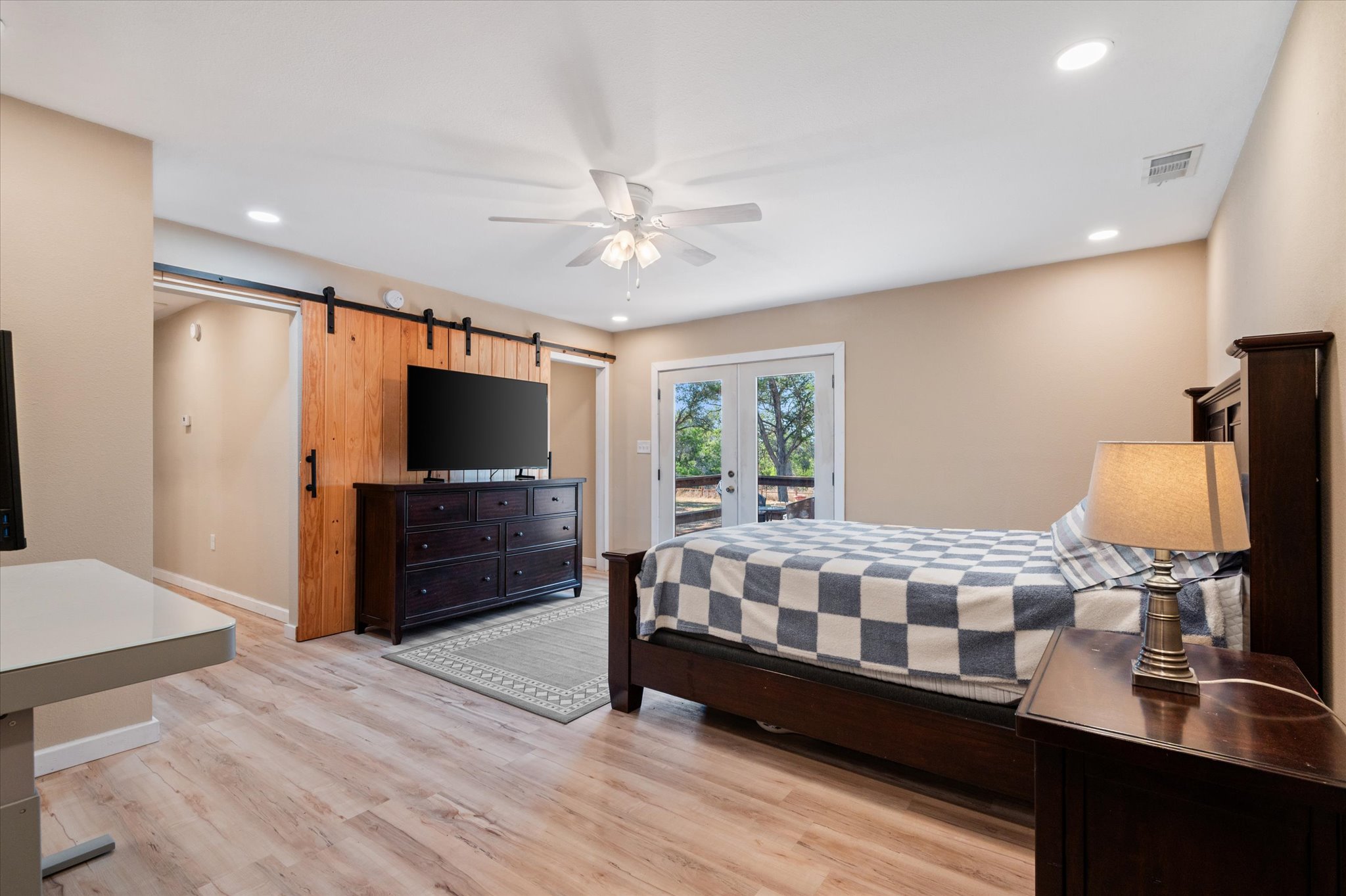 215 Go Away Road Blanco, TX 78606 - Photo 18 of 30 Primary Bedroom, dded in 2023, with ceiling fan and vinyl wood like flooring, walk-in closet and in-suite full bath. Even room for a desk! Recessed lighting and french doors that lead to the backyard porch deck.