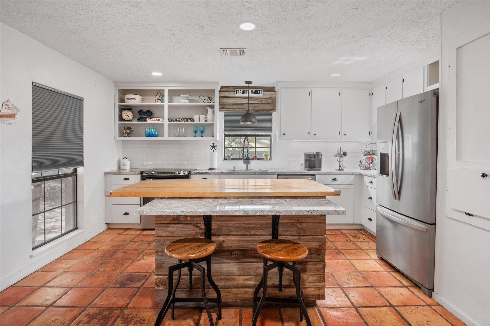 215 Go Away Road Blanco, TX 78606 - Photo 7 of 30 Bright farmhouse-style kitchen with island, open shelving, stainless appliances, and plenty of prep space.