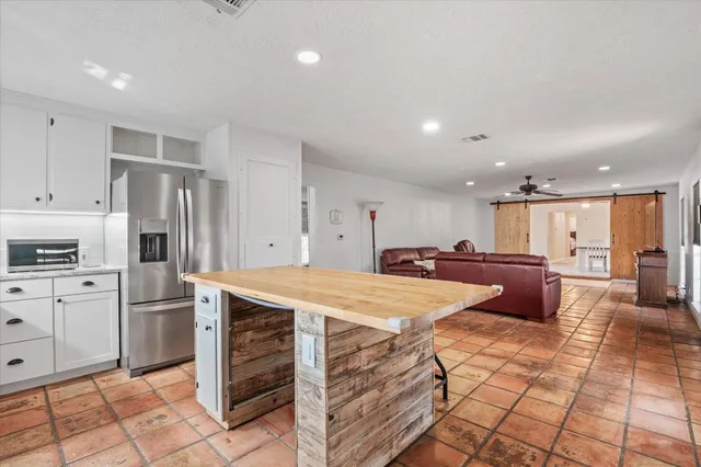 a kitchen with stainless steel appliances kitchen island granite countertop a refrigerator and a sink