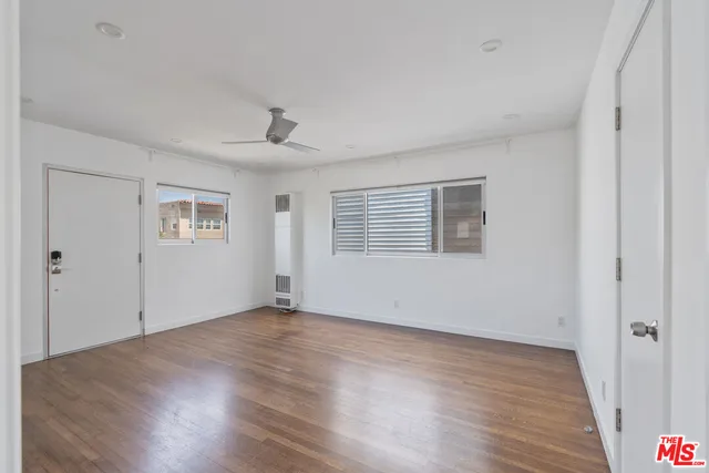 a view of an empty room with wooden floor and a window