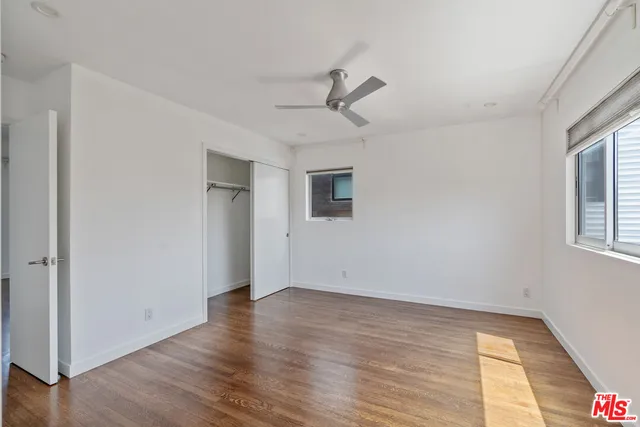 a view of empty room with wooden floor and fan
