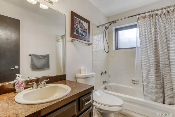 a bathroom with a granite countertop sink toilet a mirror a shower and a bathtub