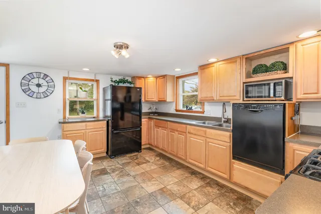 a kitchen with stainless steel appliances granite countertop a refrigerator a stove top oven and a dining table with garden view
