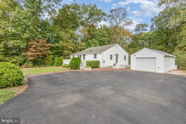 a view of house and a yard with large trees
