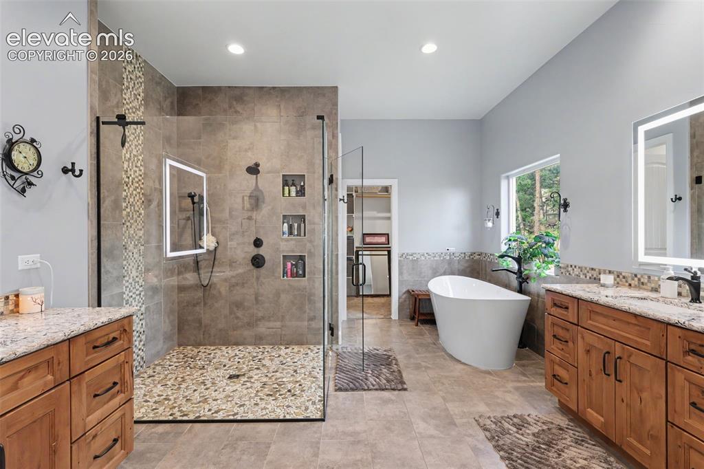 21 Leaming Road Colorado Springs, CO 80906 - Photo 28 of 48 Spacious bathroom featuring a frameless glass shower with pebble flooring and built-in niches