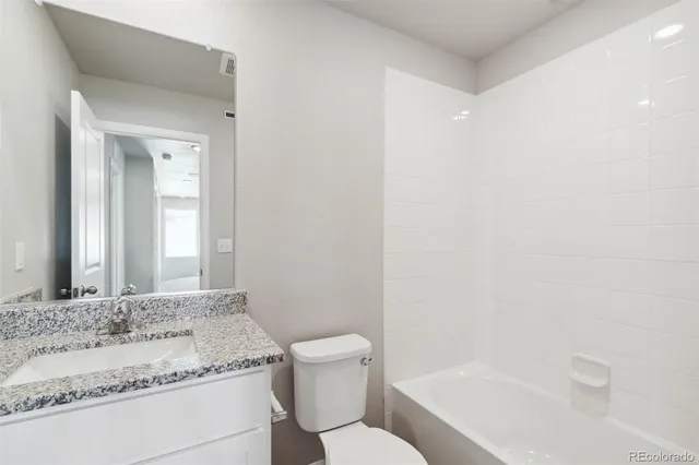 a bathroom with a granite countertop sink a toilet and shower