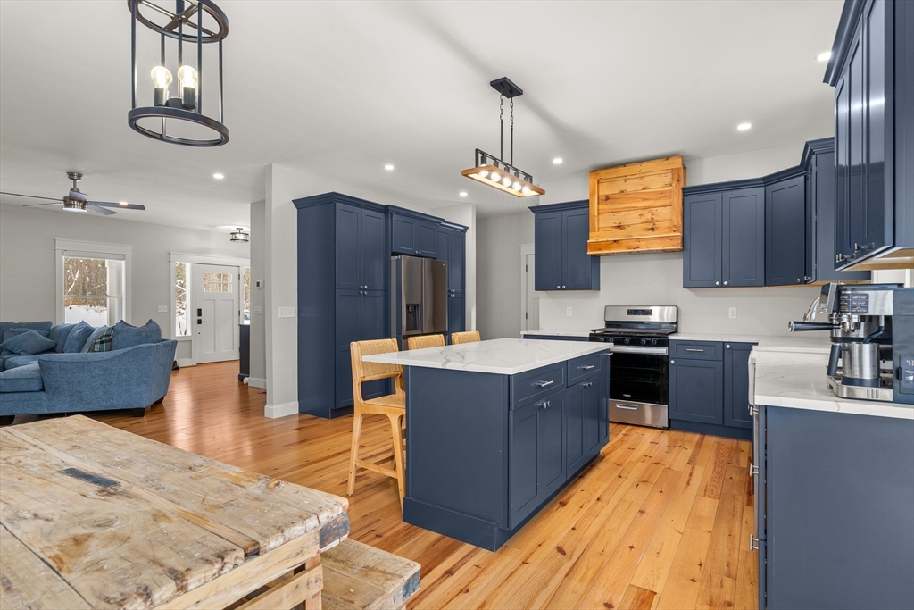 654 Skyline Trail Chester, MA 01011 - Photo 8 of 32 a large kitchen with stainless steel appliances kitchen island granite countertop a table chairs in it and a wooden floors