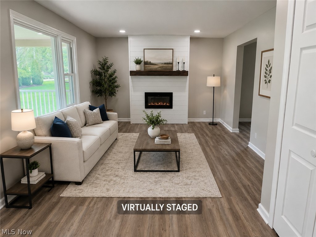 6666 Clingan Road Youngstown, OH 44514 - Photo 10 of 41 Spacious living area featuring wood-finish flooring, recessed lighting, and a modern electric fireplace with shiplap surround and a wood mantel