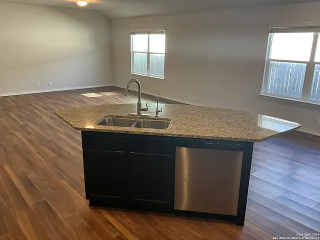 a kitchen with granite countertop a sink and wooden floor