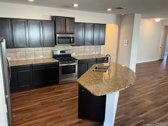 a kitchen with kitchen island granite countertop stainless steel appliances and wooden cabinets
