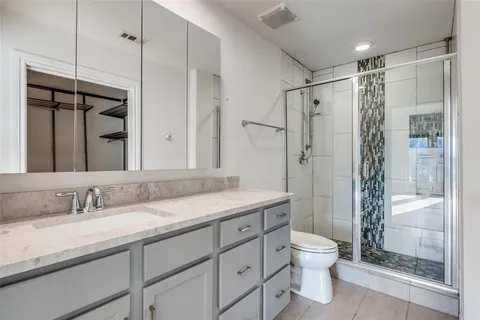 a bathroom with a granite countertop sink a toilet and shower