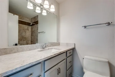 a bathroom with a granite countertop sink a toilet and a mirror