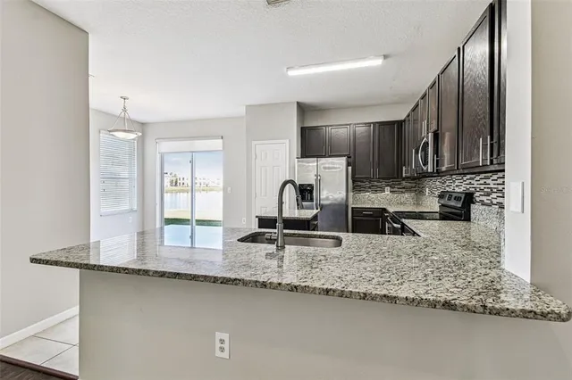 a kitchen with kitchen island granite countertop a sink stove and cabinets