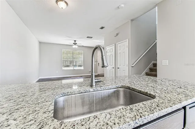 a kitchen with a granite countertop sink and natural light