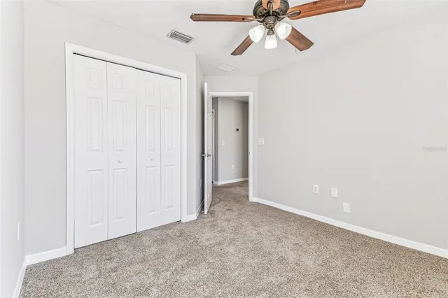 an empty room with windows and ceiling fan