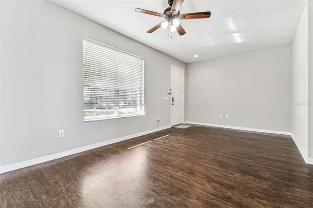 a view of an empty room with wooden floor and a window