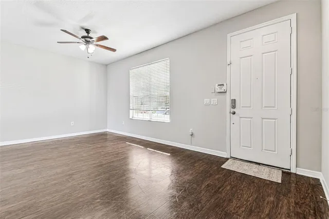 an empty room with wooden floor closet and windows