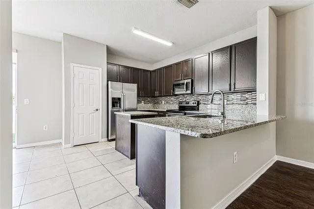 a kitchen with stainless steel appliances granite countertop a stove a sink and a refrigerator with wooden floor