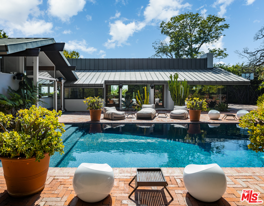 1375 Summitridge Place Beverly Hills, CA 90210 - Photo 18 of 21 a view of a patio with couches table and chairs under an umbrella with a fire pit