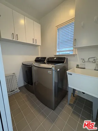 a utility room with a sink a stove and cabinets