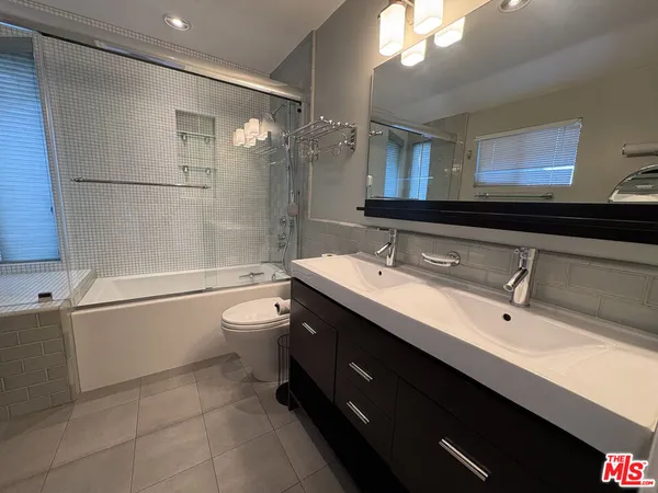 a bathroom with a double vanity sink toilet mirror and shower