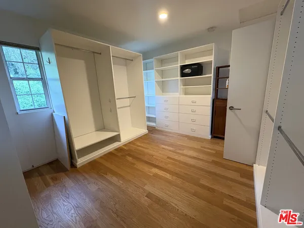 a view of empty room with wooden floor and window
