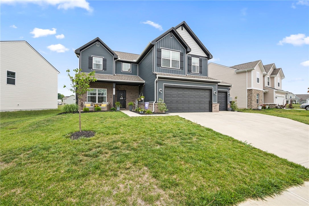 A welcoming front facade showcases a dual-bay garage, a covered entry, and an ample lawn.