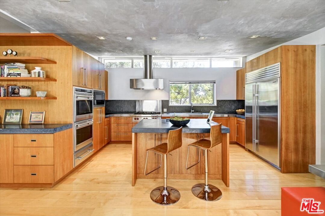 18084 Rancho Street Encino, CA 91316 - Photo 19 of 45 a kitchen with stainless steel appliances kitchen island granite countertop a table chairs in it and a window