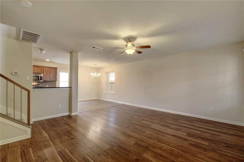 476 Nottingham Loop Kyle, TX 78640 - Photo 5 of 29 an empty room with wooden floor and a kitchen