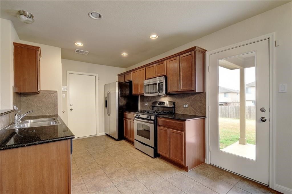 476 Nottingham Loop Kyle, TX 78640 - Photo 6 of 29 a kitchen with stainless steel appliances granite countertop a stove a sink and a refrigerator