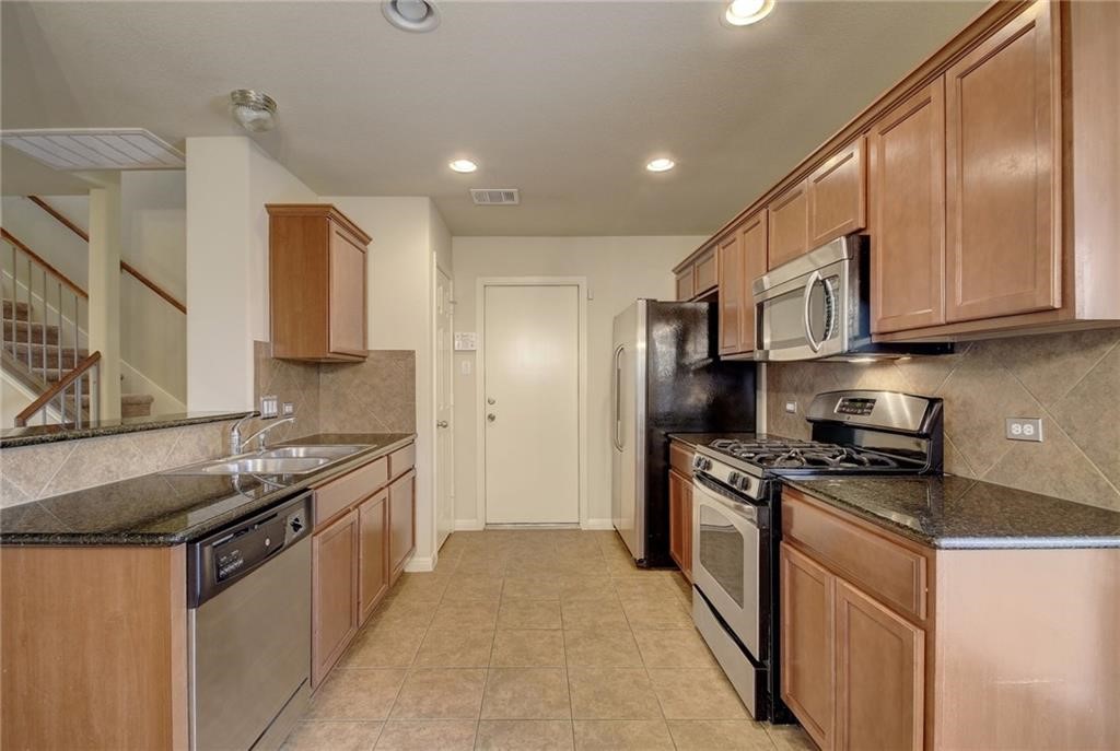476 Nottingham Loop Kyle, TX 78640 - Photo 8 of 29 a kitchen with stainless steel appliances granite countertop a stove a sink and a refrigerator