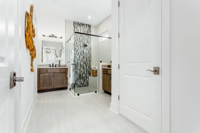 a bathroom with a double vanity sink a mirror a shower and a glass door