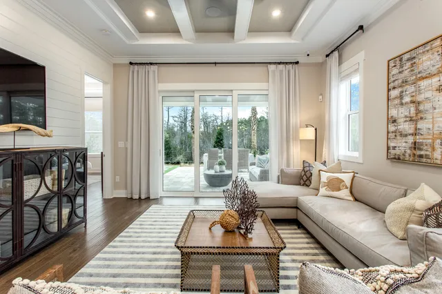 a living room with furniture a flat screen tv and a floor to ceiling window