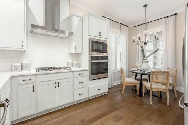 a kitchen with stainless steel appliances white cabinets and wooden floors