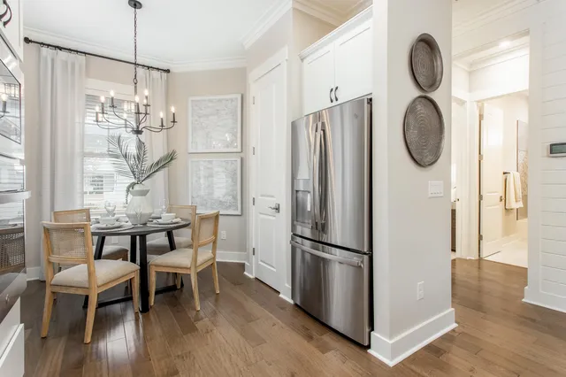 a kitchen with refrigerator a table chairs and wooden floor