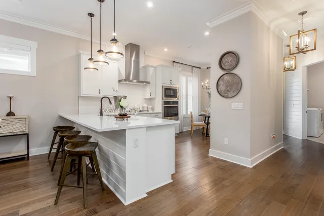 a kitchen with a table chairs a sink dishwasher and a stove with wooden floor